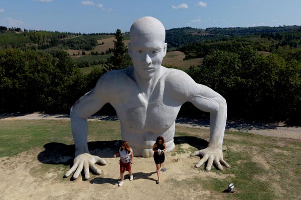 Una imagen tomada desde un dron muestra a los visitantes posando junto a una de las figuras humanas gigantes de la instalación "Presenze" (conocida comúnmente como Los Gigantes de Peccioli), de Naturaliter, en el anfiteatro de Fonte Mazzola, en Peccioli, Italia. - Sputnik Mundo