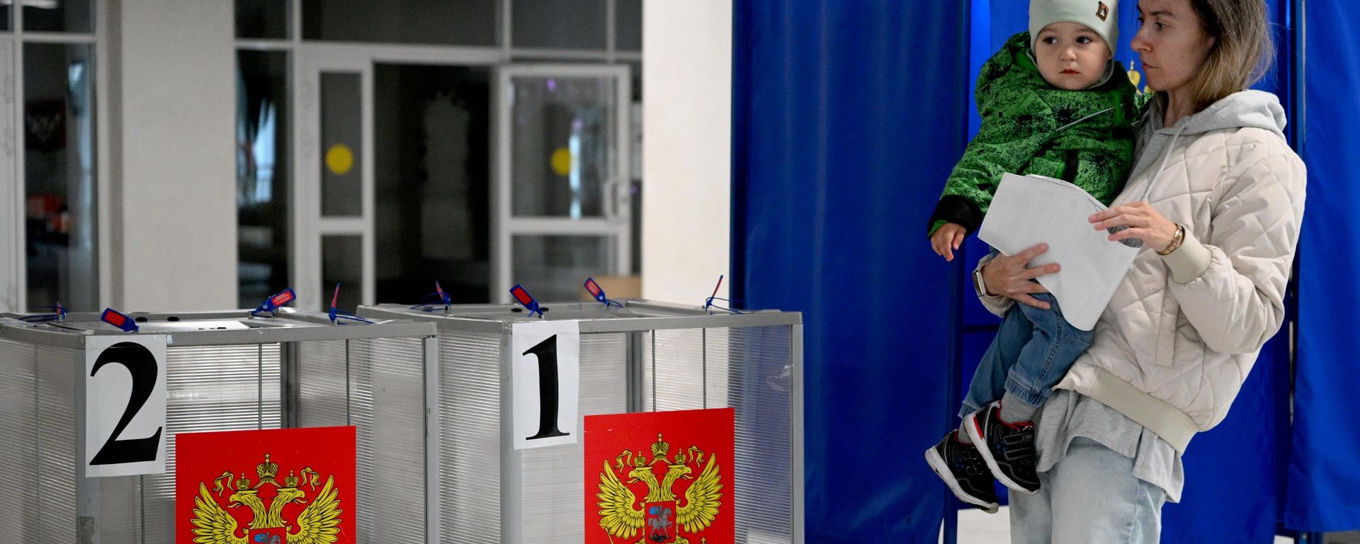 Una mujer con un niño en brazos vota en las elecciones a la Duma Estatal de Rusia de la novena legislatura - Sputnik Mundo, 1920, 20.09.2026