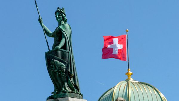 La estatua de Helvetia frente a una bandera suiza en el edificio del Parlamento suizo - Sputnik Mundo