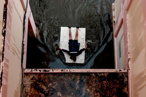 Un hombre tumbado sobre una plancha de espuma flotante en una zona inundada durante las fuertes lluvias en Bangkok, Tailandia. - Sputnik Mundo