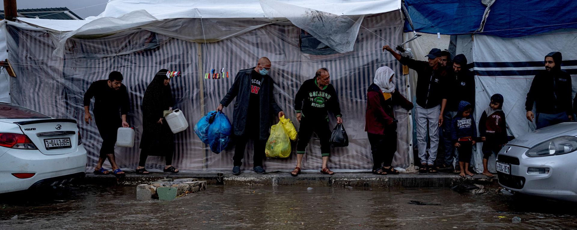 Palestinos desplazados por los bombardeos israelíes en la Franja de Gaza buscan refugio de la lluvia invernal en un campamento de tiendas de campaña de la ONU, en la localidad sureña de Jan Yunis (Franja de Gaza), el domingo 19 de noviembre de 2023. - Sputnik Mundo, 1920, 10.10.2026