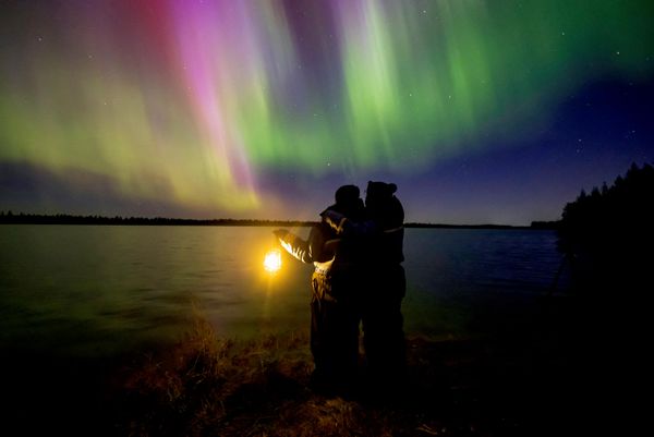 Dos personas observan la aurora boreal que ilumina el cielo sobre la ciudad de Rovaniemi, Finlandia. - Sputnik Mundo
