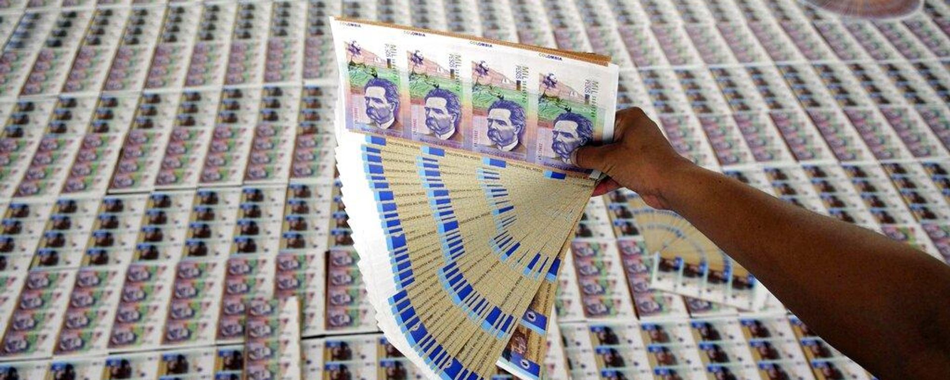 Un agente de policía muestra billetes falsificados de pesos colombianos incautados durante una presentación a los medios de comunicación en Medellín, Colombia, el 18 de septiembre de 2009  - Sputnik Mundo, 1920, 20.10.2026