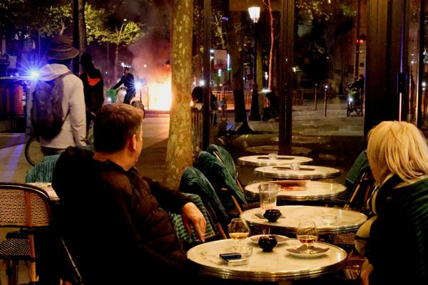 Clientes de una cafetería parisina observan el incendio provocado por alborotadores durante las protestas contra el aumento del costo de vida en Francia. - Sputnik Mundo
