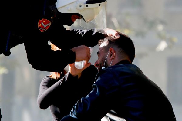 Un agente de la policía antidisturbios ayuda a un hombre afectado por el gas lacrimógeno durante una manifestación contra el Gobierno en la capital albanesa de Tirana. - Sputnik Mundo