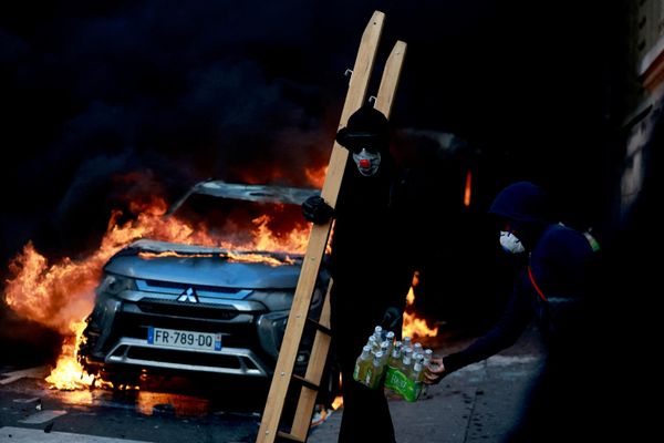 Un participante en los disturbios pasa junto a un automóvil en llamas durante una protesta contra el encarecimiento del costo de vida y del combustible en París. - Sputnik Mundo