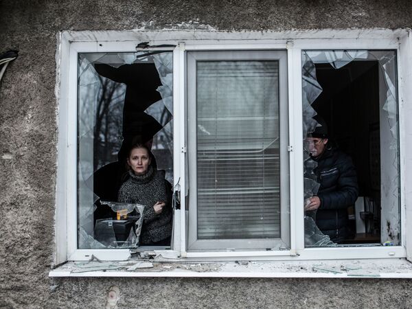 A Ukrainian woman looks through a broken window at their flat after it was hit by Ukrainian Artillery in the Voroshilovsky area, center of Donetsk, Ukraine. Sunday, Jan. 18, 2015 - Sputnik Mundo