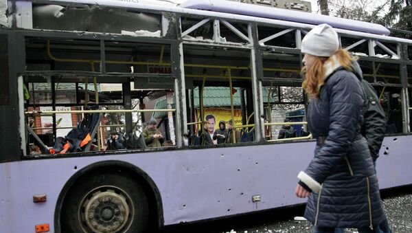 A woman walks past a damaged trolleybus in Donetsk, January 22, 2015. A woman walks past a damaged trolleybus in Donetsk, January 22, 2015. - Sputnik Mundo