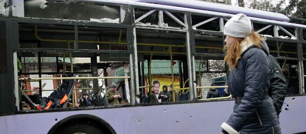 A woman walks past a damaged trolleybus in Donetsk, January 22, 2015. A woman walks past a damaged trolleybus in Donetsk, January 22, 2015. - Sputnik Mundo