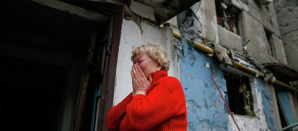 A woman reacts as she stands near a multi-storey block of flats damaged by shelling in Yenakieve town, northeast from Donetsk, February 2, 2015 - Sputnik Mundo