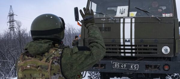 A Donetsk militia signals for a Ukrainian convoy truck to stop on the road near the Airport of Donetsk - Sputnik Mundo