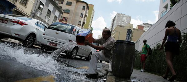 A man pours excess water on to the road after filling up his barrel in Sao Paulo February 3, 2015 - Sputnik Mundo
