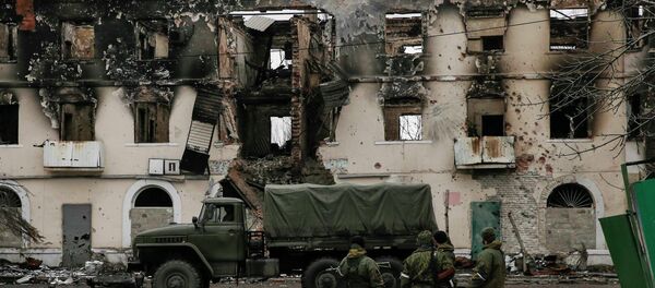 Members of the armed forces of the separatist self-proclaimed Donetsk People's Republic gather near a building destroyed during battles with the Ukrainian armed forces in Vuhlehirsk, Donetsk region, February 4, 2015 - Sputnik Mundo