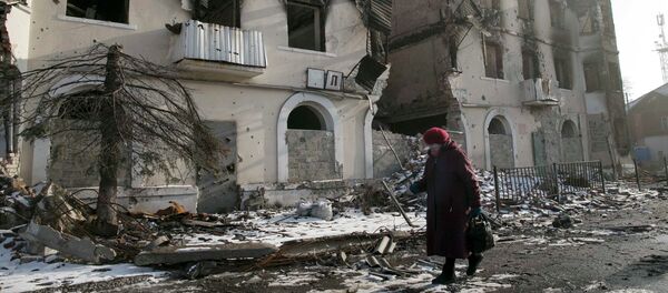 A woman walks past a damaged building in the town of Vuhlehirsk near Donetsk, Ukraine, February 14, 2015 - Sputnik Mundo