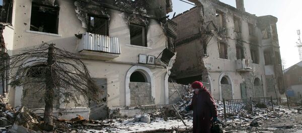 A woman walks past a damaged building in the town of Vuhlehirsk near Donetsk, Ukraine, February 14, 2015. - Sputnik Mundo