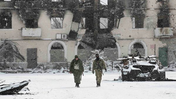 Fighters of the separatist self-proclaimed Donetsk People's Republic walk past a destroyed Ukrainian army armoured personnel carrier in the town of Vuhlehirsk, about 10 km (6 miles) to the west of Debaltseve, February 16, 2015 - Sputnik Mundo