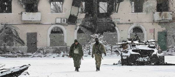 Fighters of the separatist self-proclaimed Donetsk People's Republic walk past a destroyed Ukrainian army armoured personnel carrier in the town of Vuhlehirsk, about 10 km (6 miles) to the west of Debaltseve, February 16, 2015 - Sputnik Mundo