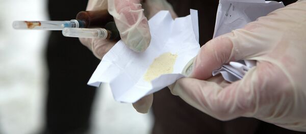 Un policía del departamento de narcóticos sostiene en la mano dos jeringuillas y una dosis de heroína (archivo) - Sputnik Mundo