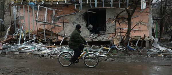 Житель города Дебальцево едет на велосипеде мимо разрушенного в результате обстрелов во время боевых действий жилого дома. - Sputnik Mundo