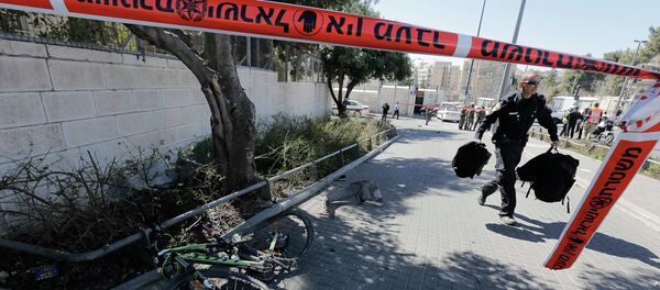 An Israeli policeman, holding bags belonging to pedestrians injured during an attack, walks past a bicycle damaged during the attack in Jerusalem March 6, 2015 - Sputnik Mundo