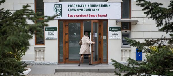 Женщина входит в здание Российского национального коммерческого банка в городе Севастополе - Sputnik Mundo