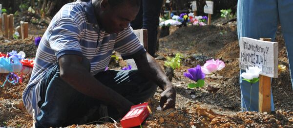Sobreviviente del virus Ébola Stanley Juah llora en la tumba de su hijo en un cementerio para las víctimas de Ébola - Sputnik Mundo