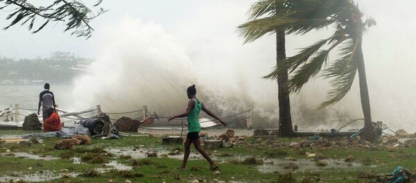 Local residents walk past debris as a wave breaks nearby in Port Vila, the capital city of the Pacific island nation of Vanuatu March 14, 2015. - Sputnik Mundo