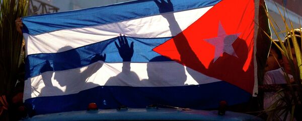 Children's shadows are cast on a Cuban national flag as they take part in a caravan tribute marking the 56th anniversary of the original street party that greeted a triumphant Castro and his rebel army, in Regla, Cuba, Thursday, Jan. 8, 2015 - Sputnik Mundo