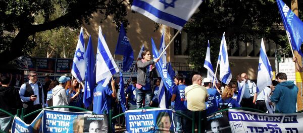 A woman waves an Israeli national flag outside a polling station in Tel Aviv March 17, 2015 - Sputnik Mundo