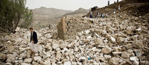 Yemenis stand amid the rubble of houses destroyed by Saudi-led airstrikes in a village near Sanaa - Sputnik Mundo