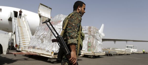 A Houthi militant walks past a shipment of emergency medical aid for the Red Cross being unloaded from a plane at Sanaa airport April 11, 2015. - Sputnik Mundo