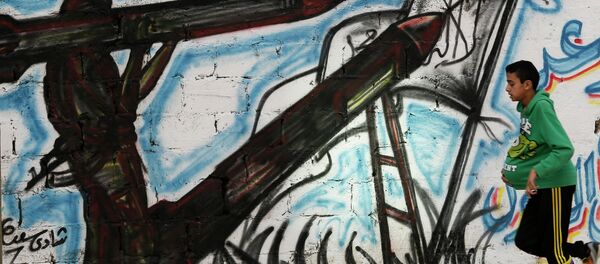 Un niño palestino corre en frente de una pared con graffiti en Gaza. 24 de abril de 2015 - Sputnik Mundo