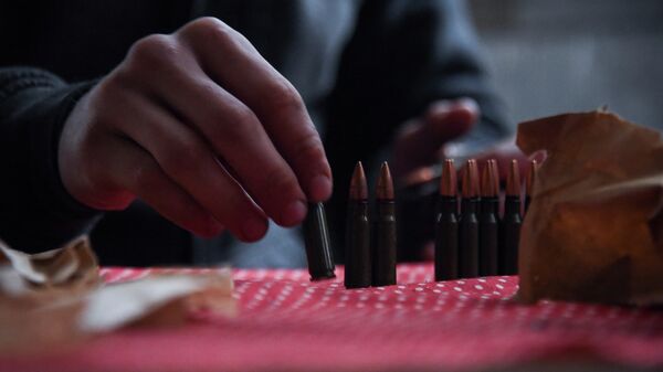 Ukrainian soldier loads ammunition as he gets ready to guard OSCE observers near the village of Shyrokyne, eastern Ukraine - Sputnik Mundo