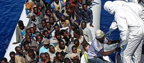 Migrants crowd and inflatable dinghy as rescue vassel  Denaro  of the Italian Coast Guard approaches them, off the Libyan coast, in the Mediterranean Sea, Wednesday, April 22, 2015 - Sputnik Mundo