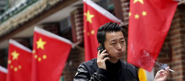 A smoker walks past Chinese national flags in front of a restaurant in Beijing, China, May 11, 2015 - Sputnik Mundo