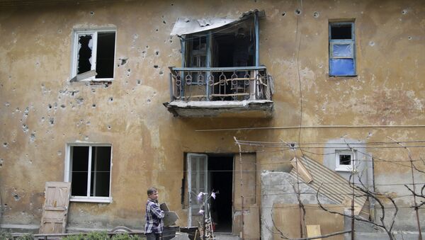 A man clears debris around a damaged residential building, which according to locals was caused by recent shelling, in Donetsk - Sputnik Mundo