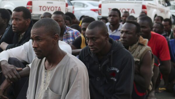 Suspected migrants sit on the ground after being detained in an early morning raid conducted by Libyan security forces in Tripoli, Libya - Sputnik Mundo