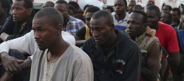 Suspected migrants sit on the ground after being detained in an early morning raid conducted by Libyan security forces in Tripoli, Libya - Sputnik Mundo