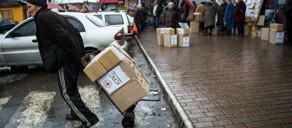 A man drags a trolley with aid as he leaves a Red Cross distribution center in Debaltseve - Sputnik Mundo