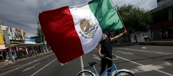 Un manifestante por el caso Ayotzinapa lleva una bandera mexicana - Sputnik Mundo