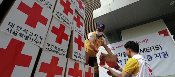Los miembros de la Cruz Roja de Corea del Sur descargan  un camión con ayuda para las personas que se sospecha de la infección - Sputnik Mundo