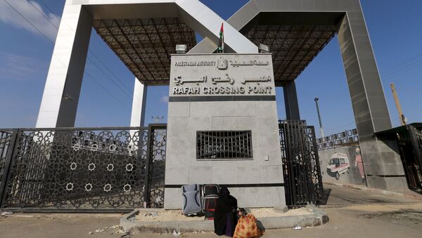 A Palestinian woman sits in front of the gate of Rafah border crossing as she waits for a travel permit to cross into Egypt, in Rafah in the southern Gaza Strip June 14, 2015. - Sputnik Mundo