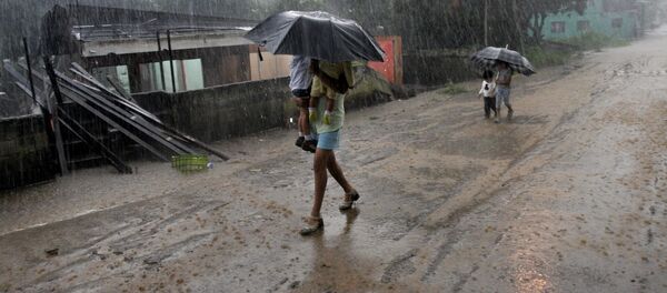 A woman carries her children in the rain as she walks by homes destroyed by flooding in Alajuela, Costa Rica - Sputnik Mundo