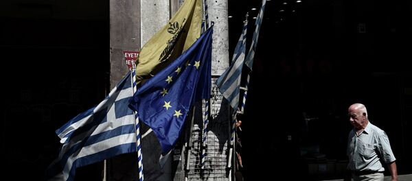 Un hombre camina delante de las banderas de UE y Grecia en el centro de Atenas. 13 de julio de 2015 - Sputnik Mundo