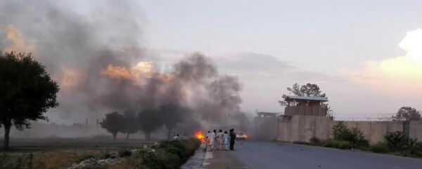 Afghan men watch the aftermath of a suicide car bomb attack at Camp Chapman in Khost province on July 12, 2015 - Sputnik Mundo