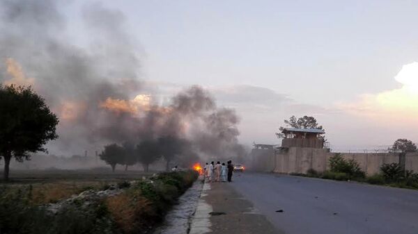 Afghan men watch the aftermath of a suicide car bomb attack at Camp Chapman in Khost province on July 12, 2015 - Sputnik Mundo