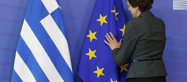 Una mujer ajusta las banderas de UE y Grecia - Sputnik Mundo