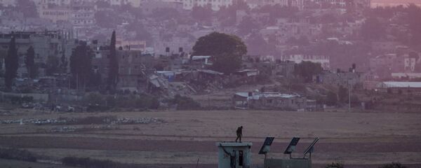 An Israeli soldier stands atop a military post on the border with northern Gaza (seen in background) July 6, 2015. - Sputnik Mundo
