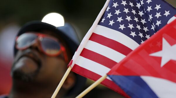 A man with small U.S. and Cuba flags stands on the sidewalk in the hours before officials raise the flag at the Cuban Embassy in Washington July 20, 2015. - Sputnik Mundo