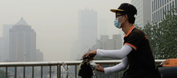 This picture taken on June 23, 2015 shows a cyclist wearing a mask in Beijing covered by heavy smog - Sputnik Mundo